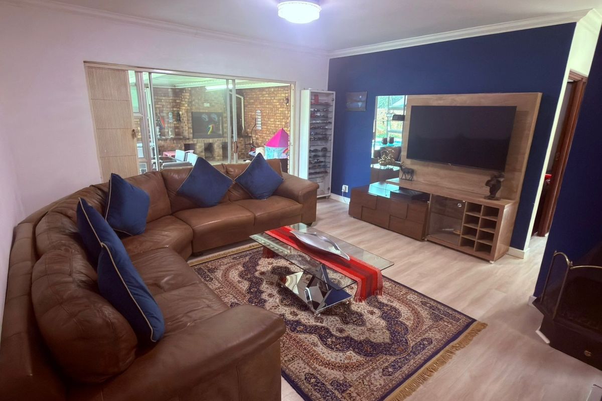 A comfortable living room featuring laminate flooring, cove cornicing, and a large sliding glass door providing access to the outdoor patio area.