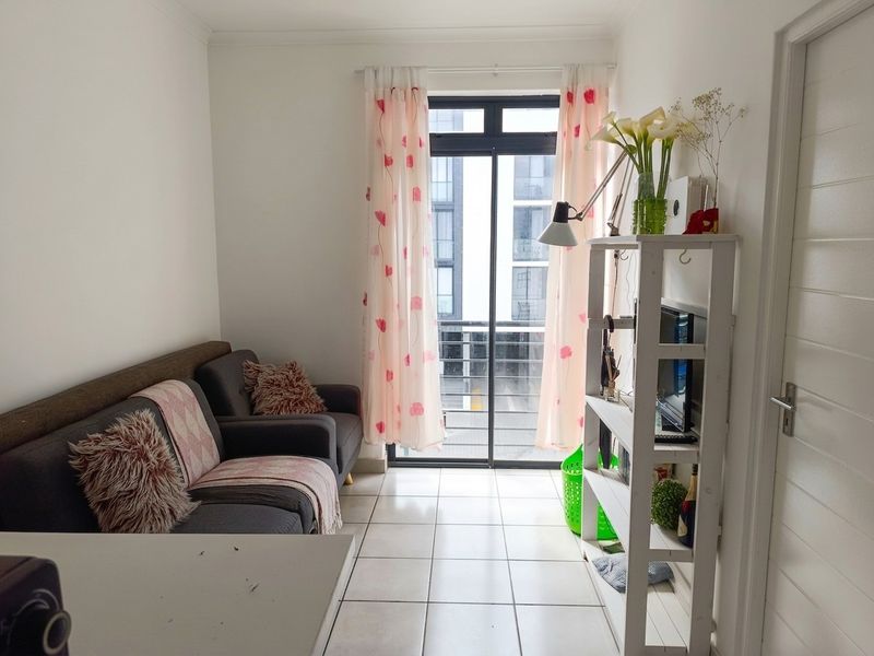A compact living area featuring tiled flooring and a sliding glass door providing access to an outdoor space.