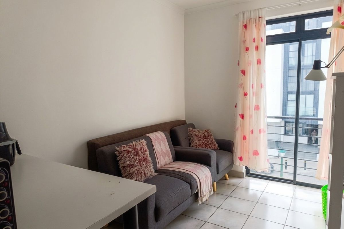 A living area featuring neutral tiled flooring and a sliding glass door providing access to a balcony.