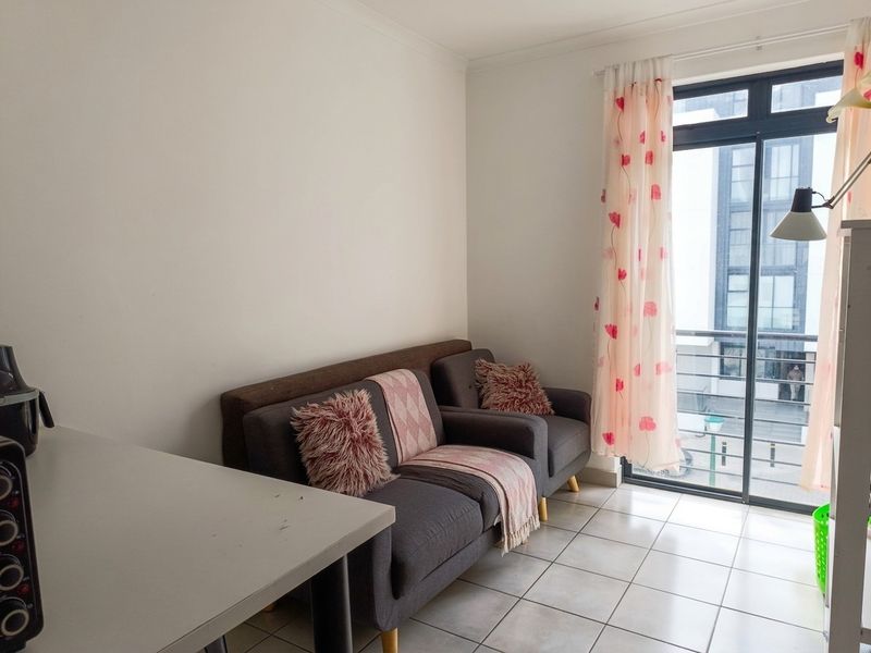 A living area featuring neutral tiled flooring and a sliding glass door providing access to a balcony.