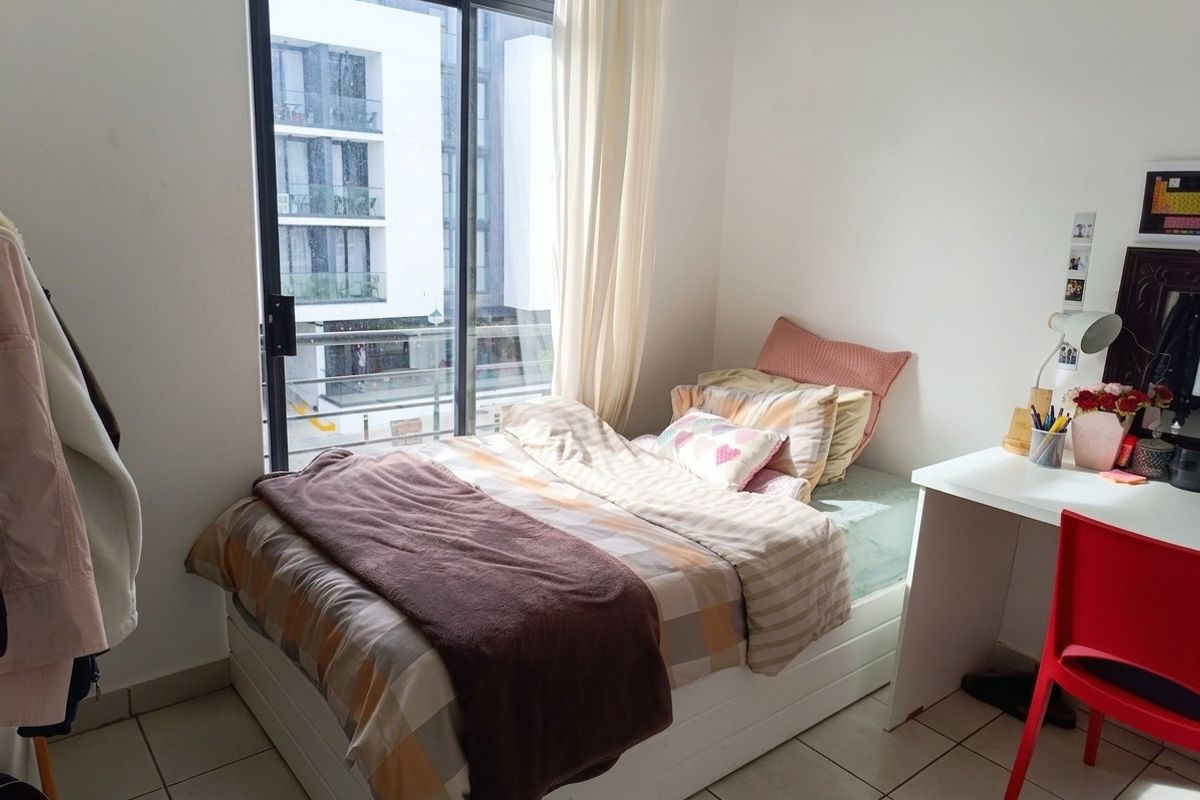 A bright bedroom featuring tiled flooring and a large sliding glass door providing natural light and access to the exterior.