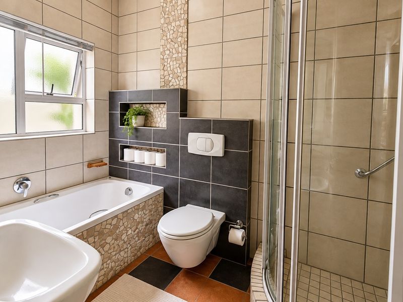 A well-maintained bathroom featuring a built-in bathtub, a separate glass shower enclosure, and a wall-hung toilet with modern tiled finishes.