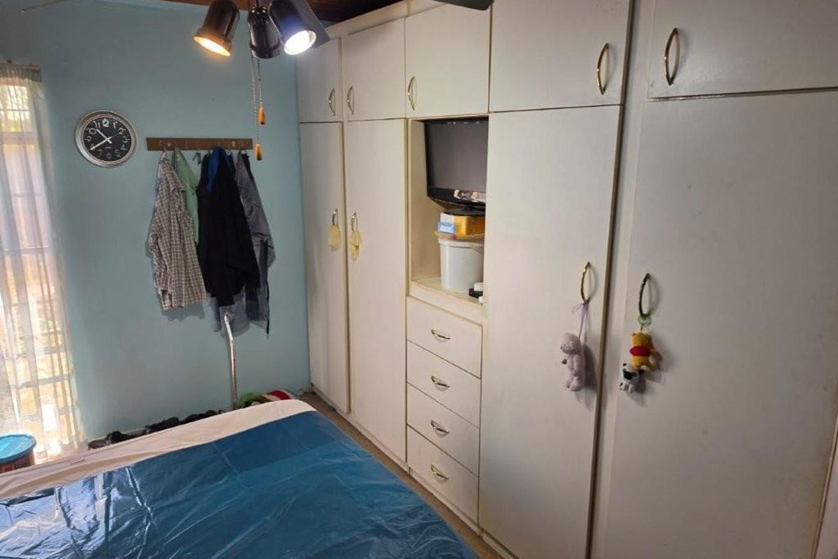 A bedroom featuring extensive built-in cupboards, a timber ceiling, and a ceiling fan, offering functional storage space.