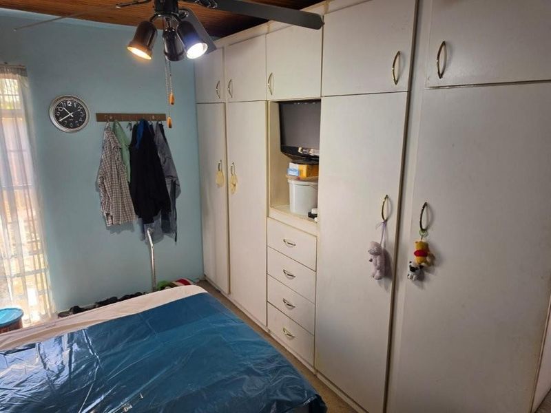 A bedroom featuring extensive built-in cupboards, a timber ceiling, and a ceiling fan, offering functional storage space.