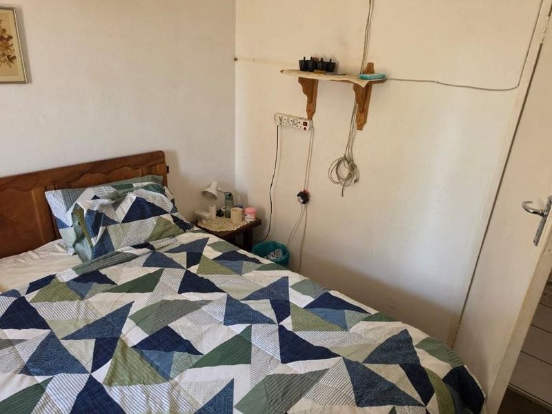 A bedroom featuring plain walls with visible electrical wiring and a standard door, requiring cosmetic updates to improve the overall finish.