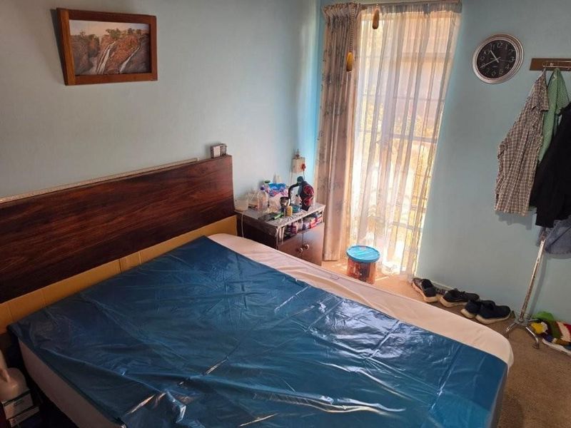 A functional bedroom featuring carpeted flooring and a sliding glass door providing natural light access.