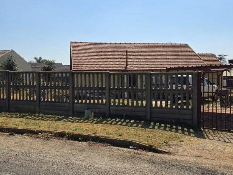 Front view of the property featuring a precast concrete boundary wall, metal driveway gate, and a tiled roof structure.
