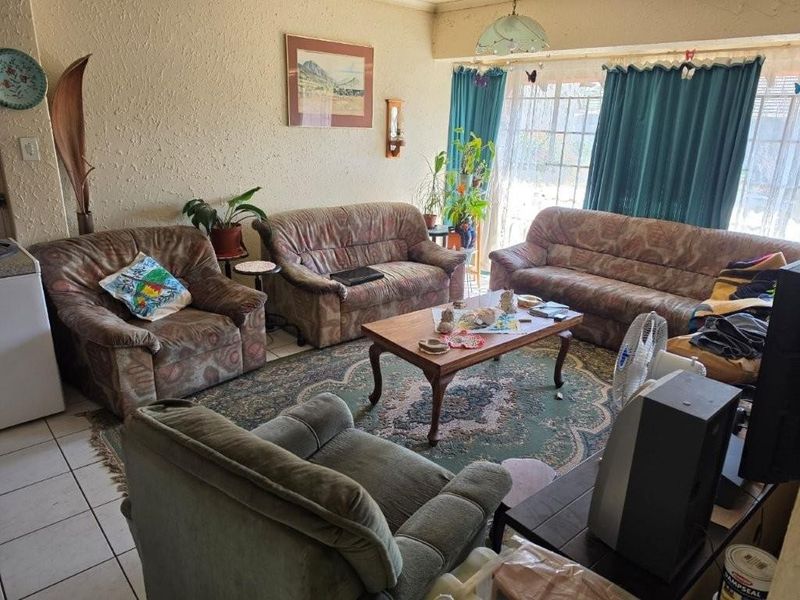 A living room featuring tiled flooring and a large sliding glass door providing natural light.