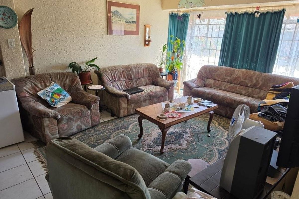 A living room featuring tiled flooring and a large sliding glass door providing natural light.