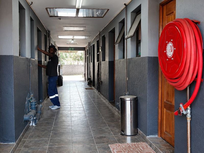 A commercial hallway featuring tiled flooring, skylights, and a wall-mounted fire hose reel, providing access to multiple rooms.