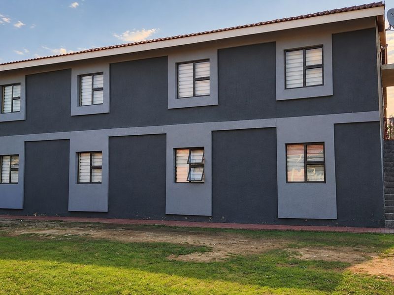 A two-story commercial building exterior featuring dark grey rendered walls, aluminium windows, and an external staircase leading to the upper level.