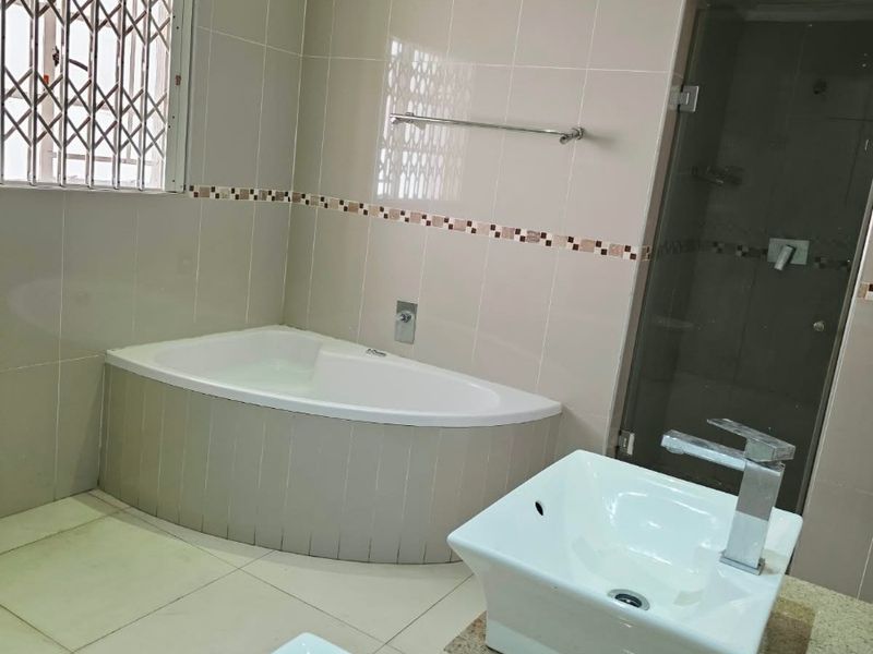 A spacious bathroom featuring a built-in bathtub, double vanity with modern basins, and a separate shower enclosure with a glass door.
