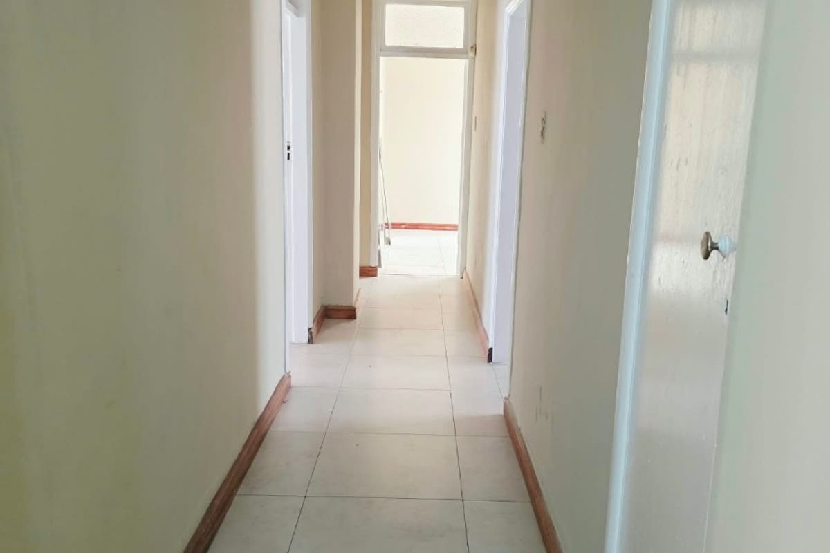 A functional, empty hallway featuring neutral tiled flooring and multiple internal doorways, providing access to various rooms within the home.