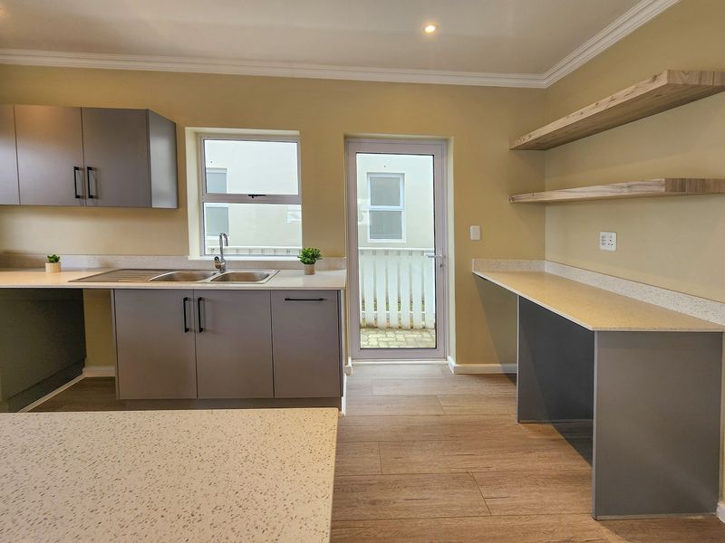 Modern kitchen featuring grey cabinetry, stone countertops, floating timber shelving, and direct access to an outdoor area.