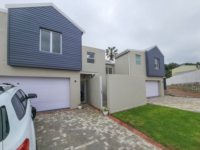 Modern double-story residential facade featuring dual garages, paved driveway, and contemporary lap siding finish.
