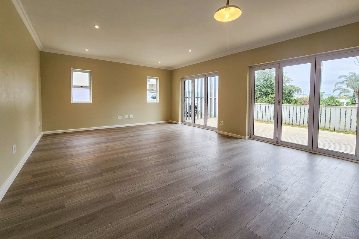 Spacious, light-filled living area featuring modern laminate flooring, recessed lighting, and large aluminium sliding doors providing seamless access to the outdoor deck.