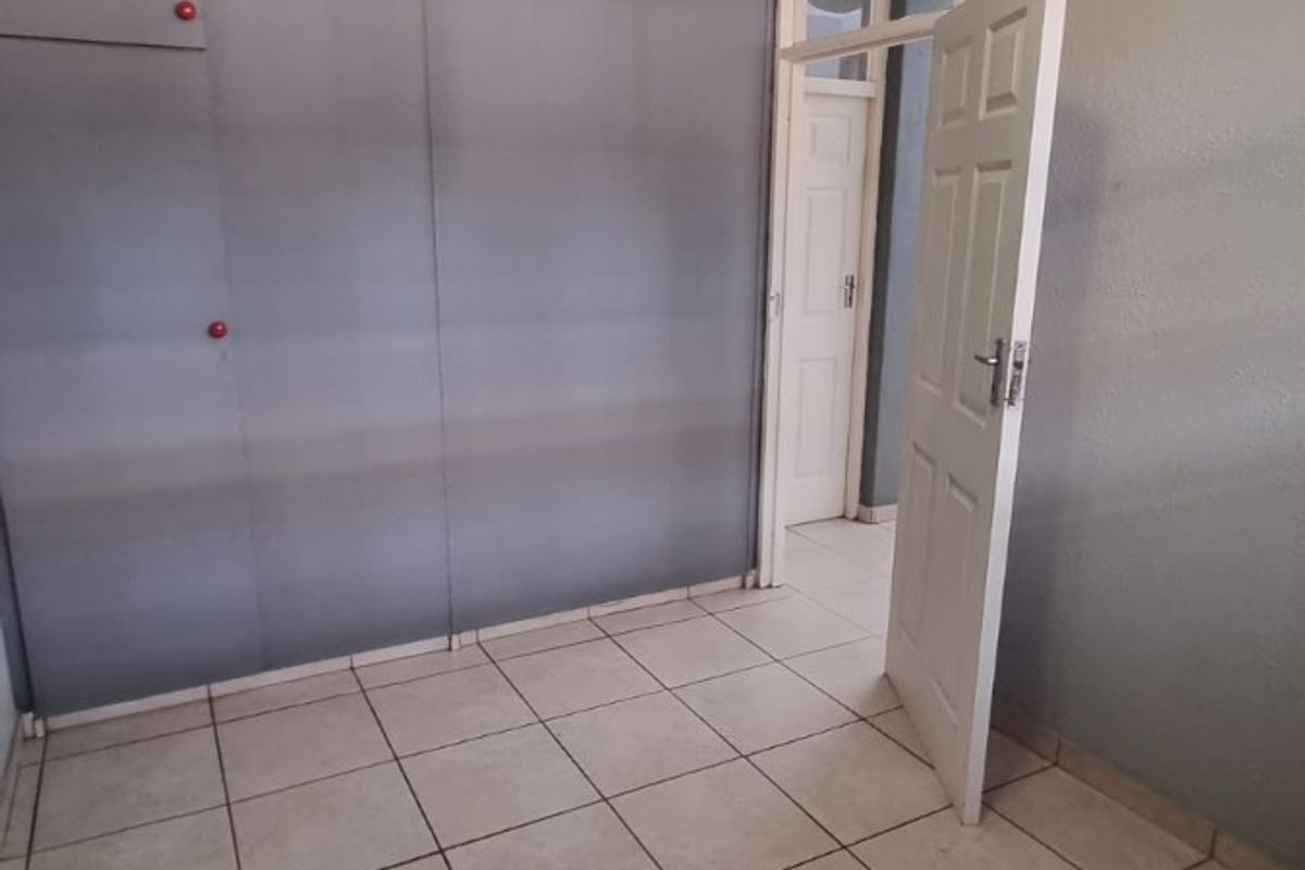 An empty bedroom featuring tiled flooring and built-in cupboards, offering a neutral space ready for personalization.