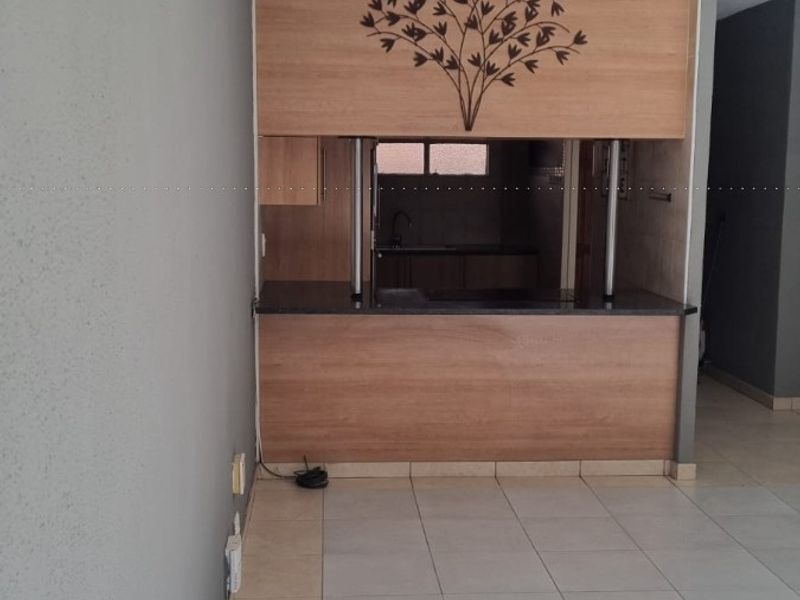 Open plan living area featuring a breakfast bar with built-in cabinetry and neutral tiled flooring throughout.
