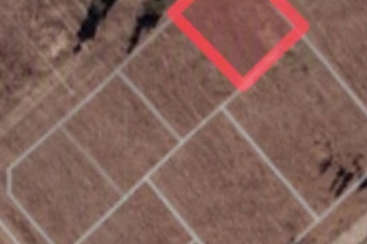 An aerial view of a vacant residential plot with property boundaries highlighted.