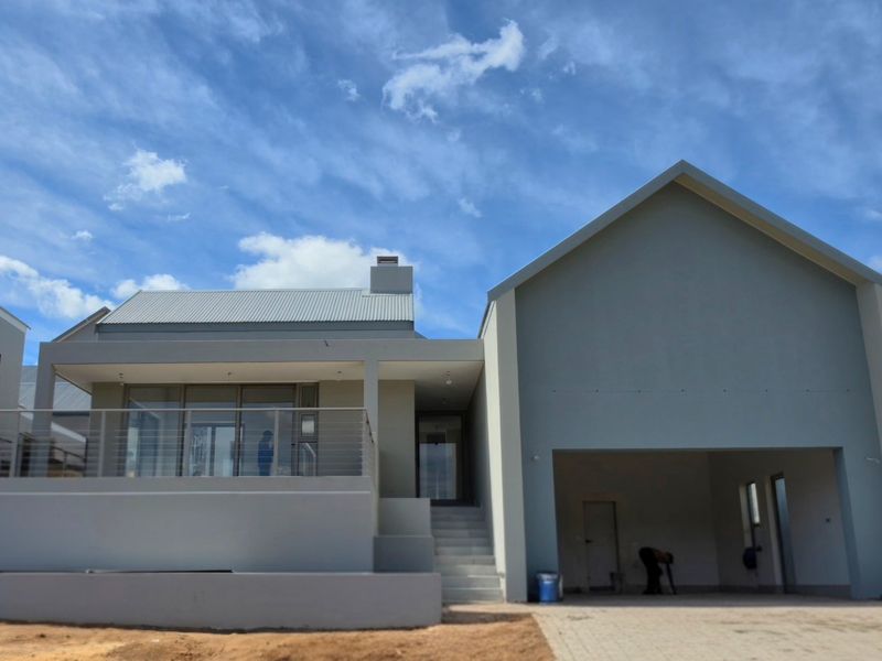 Modern architectural front elevation featuring a covered patio, double garage, and clean contemporary lines under a clear blue sky.