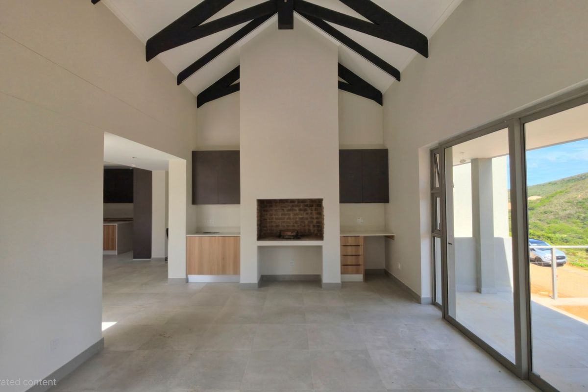 Spacious living area featuring a vaulted ceiling with exposed beams, built-in fireplace, tiled floors, and large sliding doors opening to an outdoor patio.