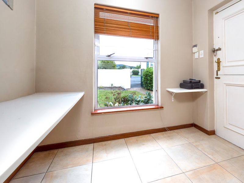 A bright and functional entry area featuring tiled flooring, built-in shelving, and a window with wooden blinds, providing a clean and welcoming space.