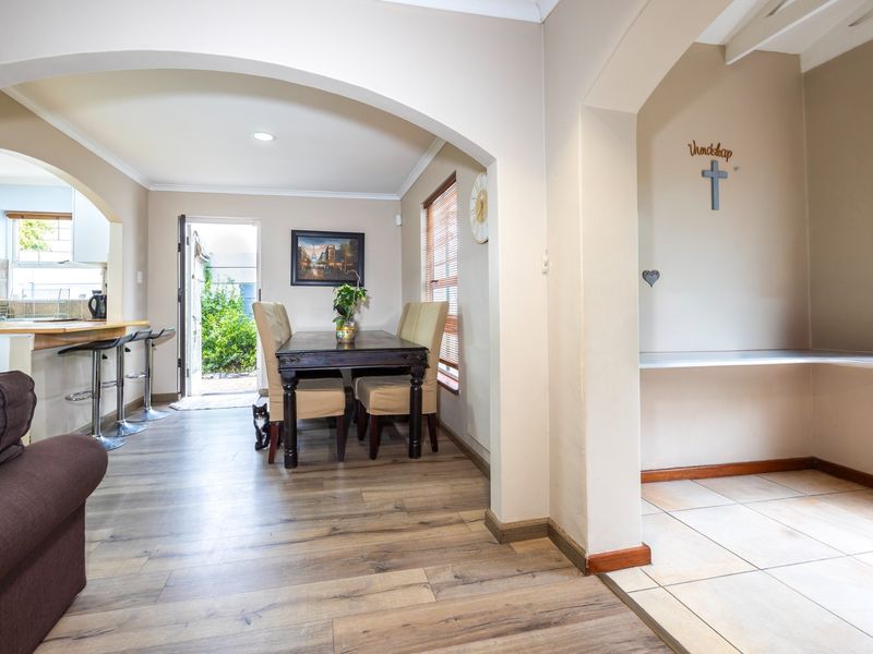 Open-plan living and dining area featuring a breakfast bar, arched transitions, and a mix of laminate and tiled flooring with direct outdoor access.