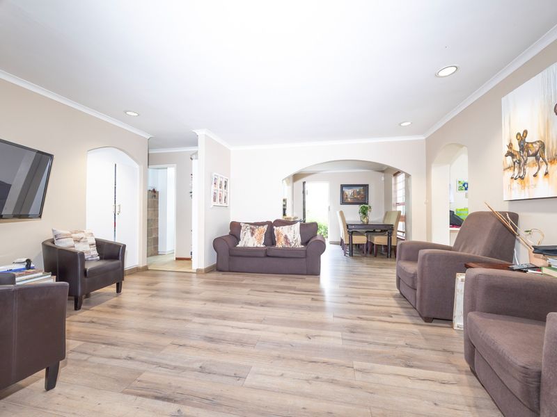 Spacious open-plan living and dining area featuring modern laminate flooring, recessed downlighting, and elegant archways connecting the living spaces.