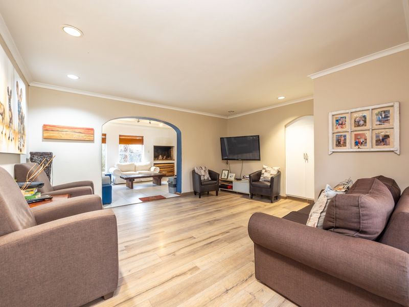 Spacious living room featuring modern laminate flooring, recessed downlighting, and an arched transition leading to an adjacent living area.