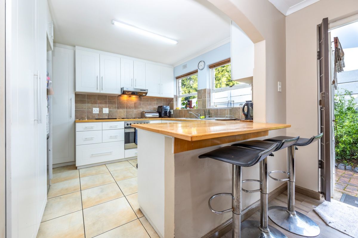 A functional kitchen featuring white cabinetry, wooden countertops, a breakfast bar, and direct access to an outdoor area.