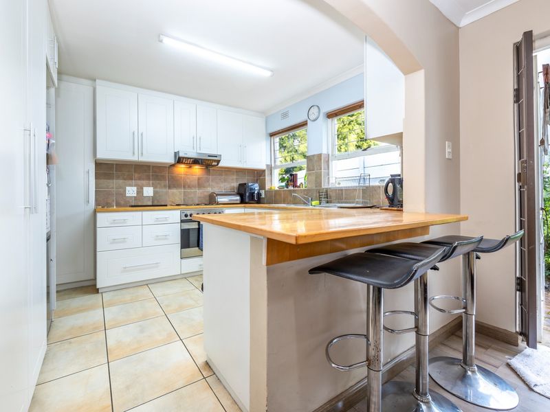 A functional kitchen featuring white cabinetry, wooden countertops, a breakfast bar, and direct access to an outdoor area.