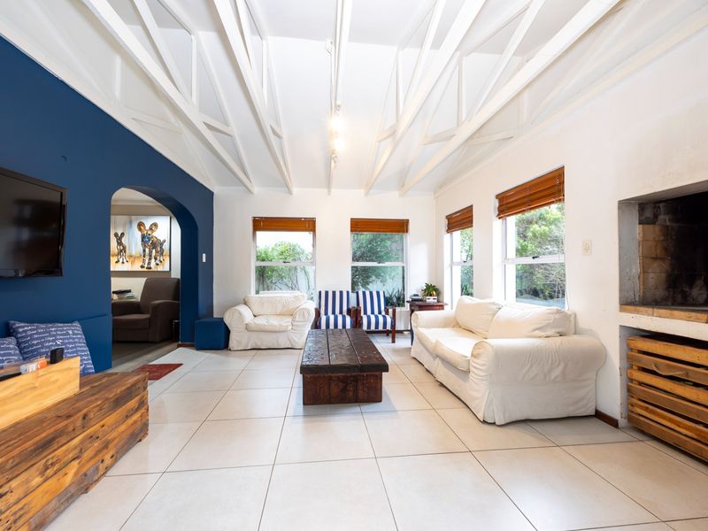 Spacious living room featuring exposed white roof trusses, tiled flooring, and a built-in fireplace with an adjacent arched entryway.