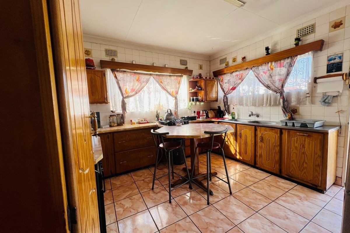 A functional kitchen featuring wooden cabinetry, tiled backsplash, and tiled flooring, offering a traditional layout with integrated sink and gas hob.