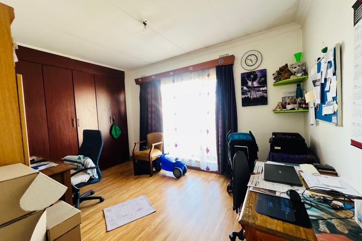 A bedroom featuring laminate flooring and built-in wooden cupboards, offering functional storage space and natural light through the window.