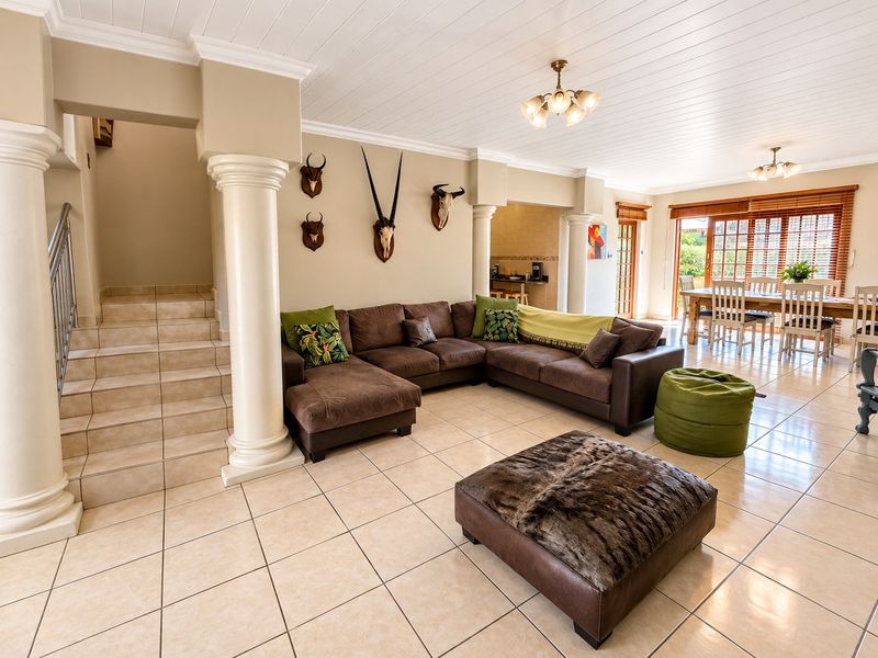 Spacious open-plan living and dining area featuring tiled floors, decorative columns, a tongue and groove ceiling, and direct access to the outdoor patio.