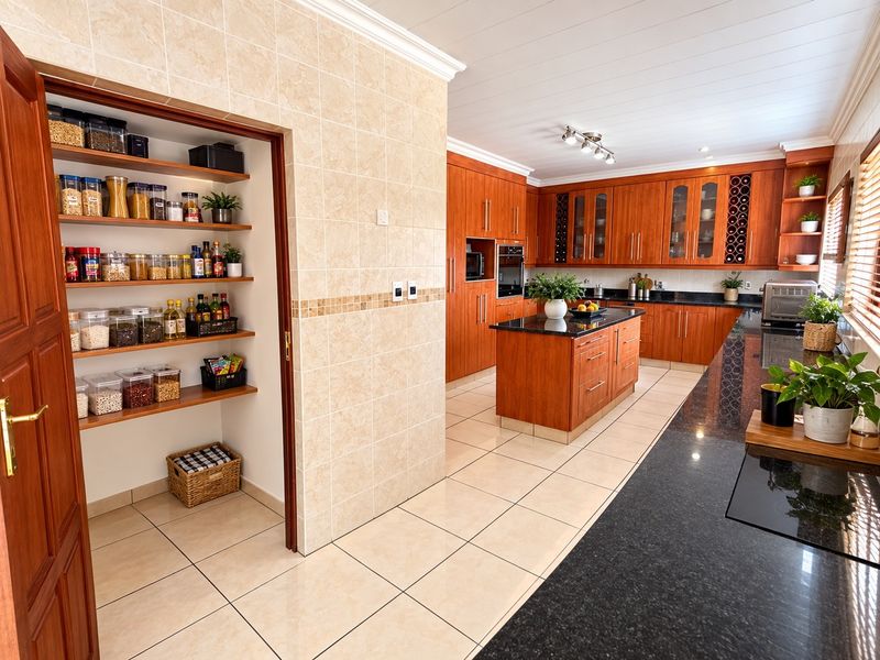 Spacious kitchen featuring warm wood cabinetry, granite countertops, a central island, and a convenient walk-in pantry with ample shelving.