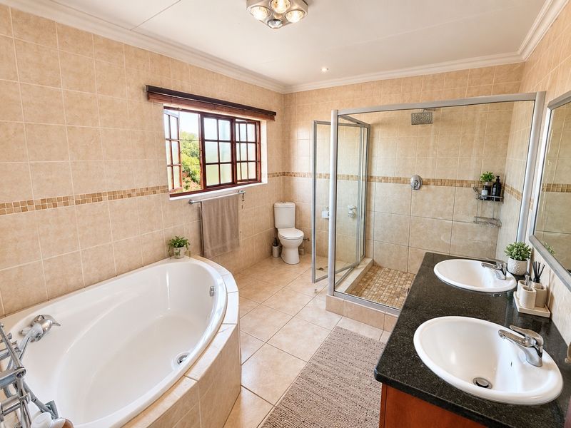Spacious bathroom featuring a built-in corner bathtub, a glass-enclosed shower, and a double vanity with granite countertop and tiled finishes.