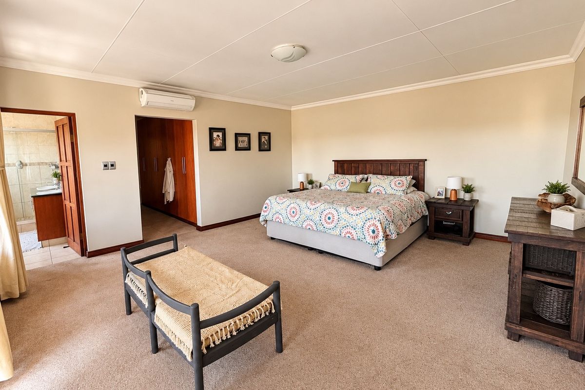 Spacious bedroom featuring neutral carpeting, built-in cabinetry, an air conditioning unit, and direct access to an en-suite bathroom.