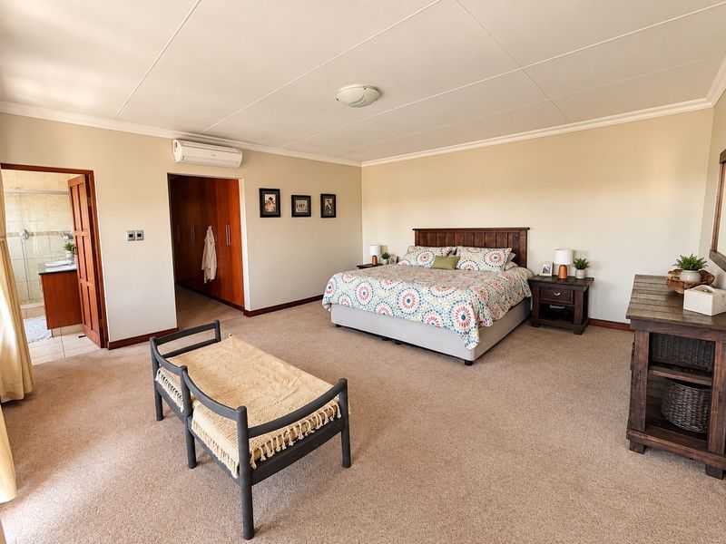 Spacious bedroom featuring neutral carpeting, built-in cabinetry, an air conditioning unit, and direct access to an en-suite bathroom.