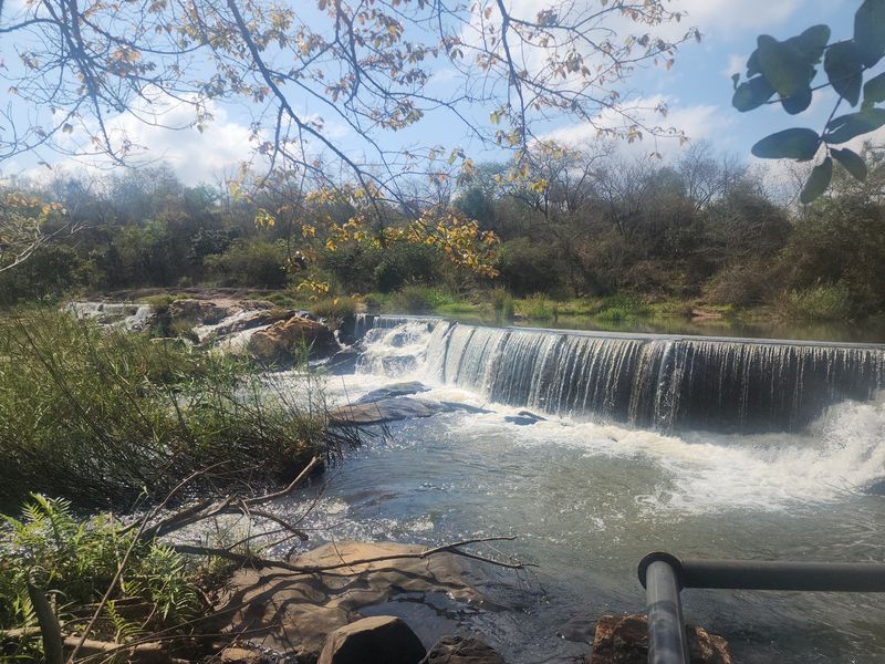 A scenic view of a natural waterfall and river flowing through the farm landscape, showcasing the property's natural water features.