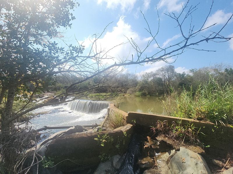 A scenic view of a river featuring a concrete weir and natural landscape, highlighting the property's water infrastructure and rural setting.