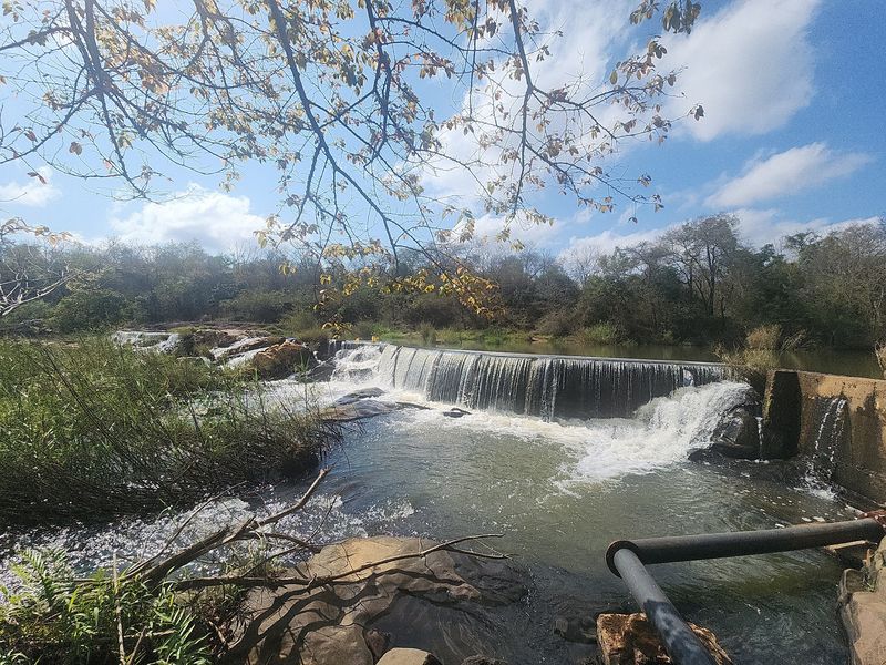 A scenic view of a natural river landscape featuring a stone weir and waterfall, highlighting the property's water features and natural surroundings.