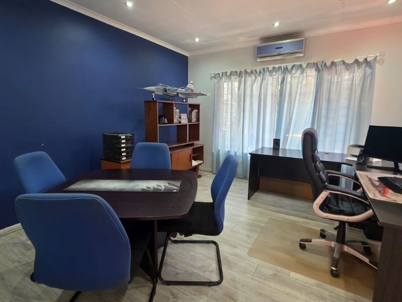 A functional home office space featuring laminate flooring, recessed lighting, and a wall-mounted air conditioning unit.