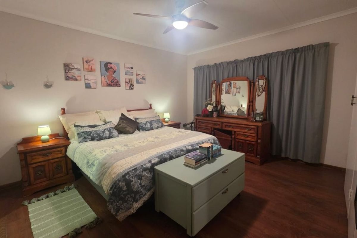 A spacious bedroom featuring laminate flooring and a ceiling fan, offering a comfortable and functional living space.