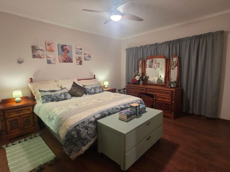 A spacious bedroom featuring laminate flooring and a ceiling fan, offering a comfortable and functional living space.