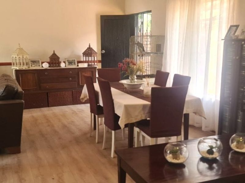 Spacious open-plan living and dining area featuring light-toned laminate flooring and large windows that provide ample natural light.