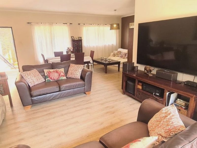 Spacious open-plan living and dining area featuring light-toned laminate flooring and neutral wall finishes, providing a versatile layout for family living.