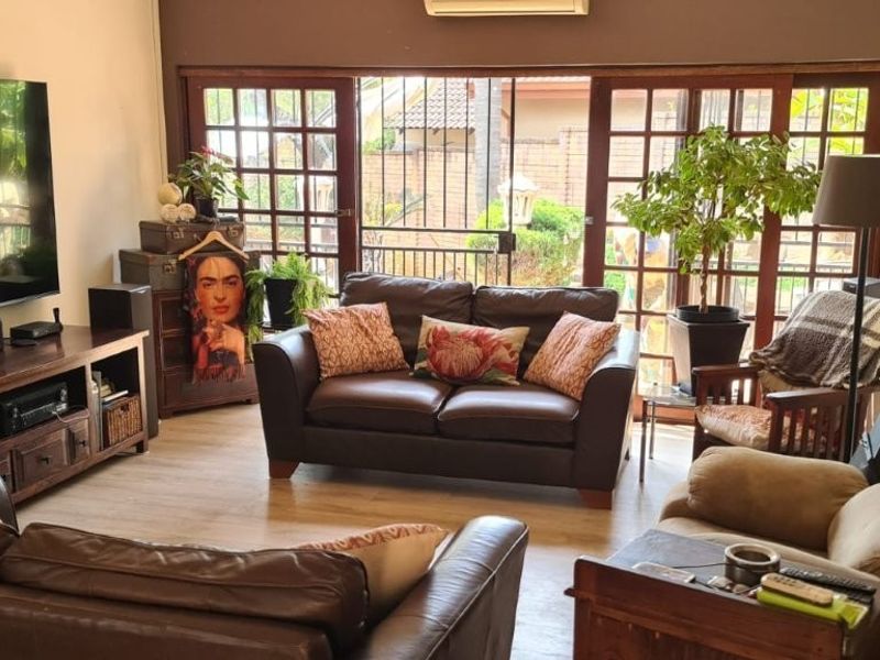 A comfortable living room featuring laminate flooring, a wood-burning fireplace, and large sliding glass doors that provide access to the outdoor area.