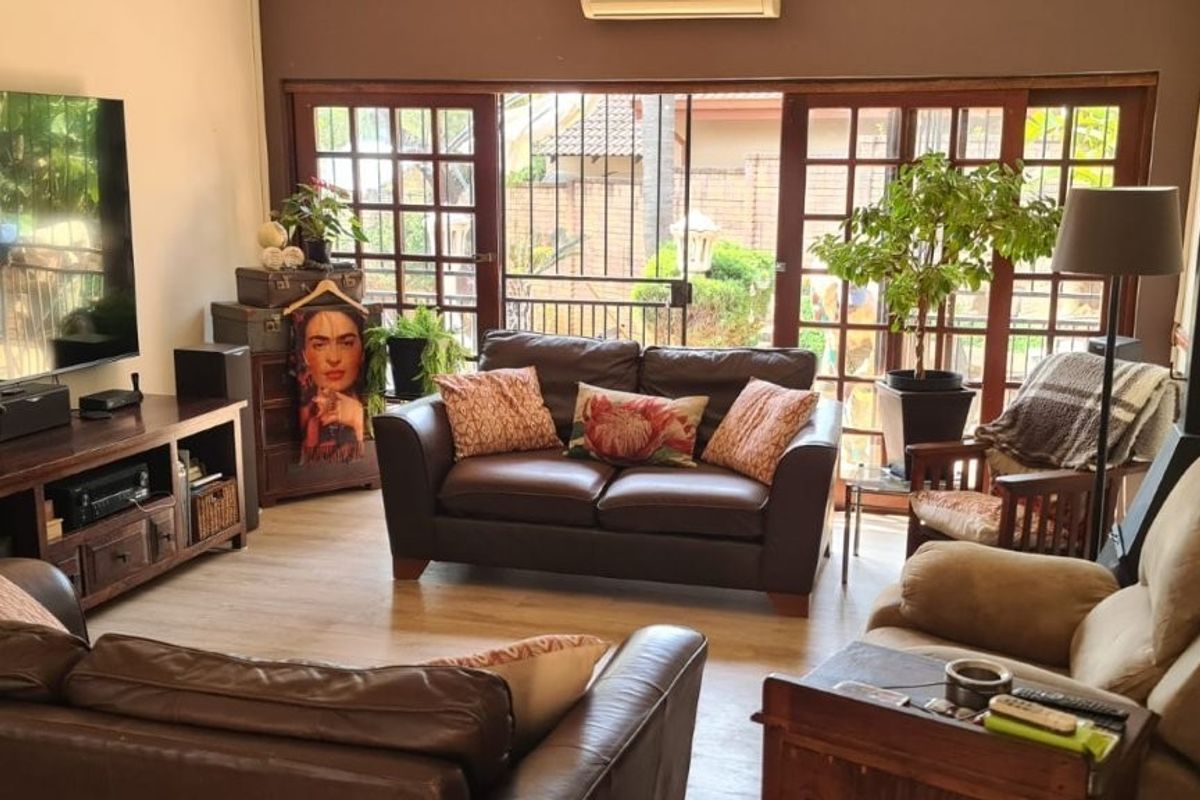 A comfortable living room featuring laminate flooring, a wood-burning fireplace, and large sliding glass doors that provide access to the outdoor area.