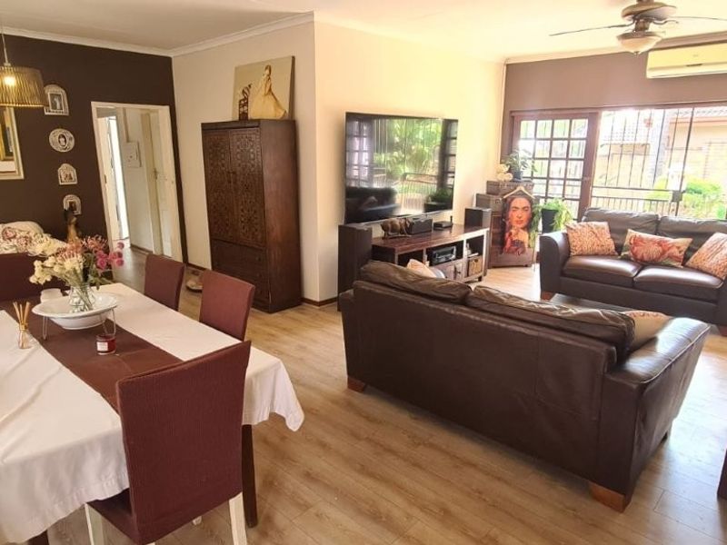 Spacious open-plan living and dining area featuring laminate flooring, a ceiling fan, and large sliding glass doors providing access to the exterior.